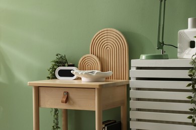 Photo of Wooden side table with stylish decor near green wall indoors, closeup
