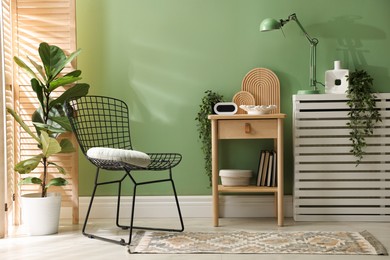 Photo of Wooden side table with stylish decor near green wall indoors