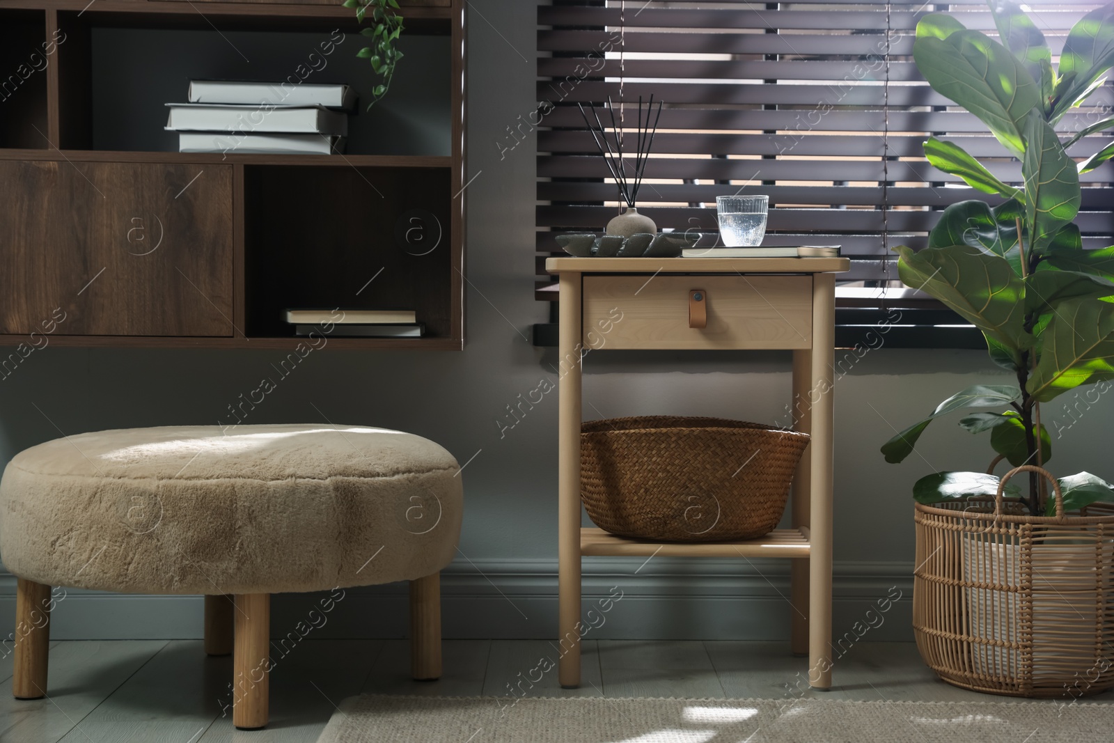 Wooden side table with glass of water, notebook, air reed diffuser and basket near window indoors Photo of Wooden side table with glass of water, notebook, air reed diffuser and basket near window indoors