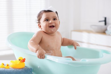 Photo of Cute little baby bathing in tub at home