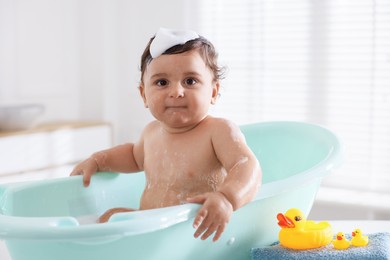 Photo of Cute little baby bathing in tub at home