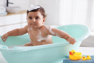 Photo of Cute little baby bathing in tub at home