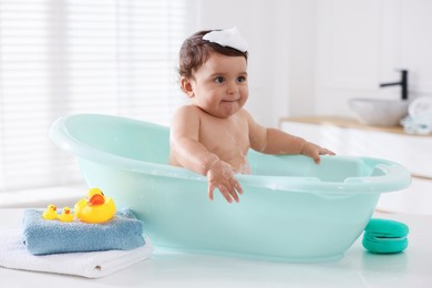 Photo of Cute little baby bathing in tub at home