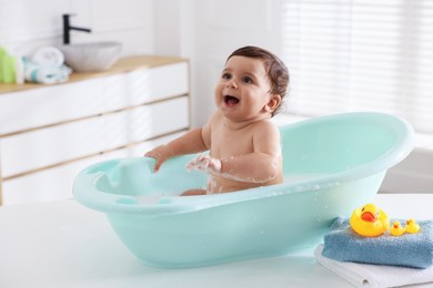 Photo of Cute little baby bathing in tub at home
