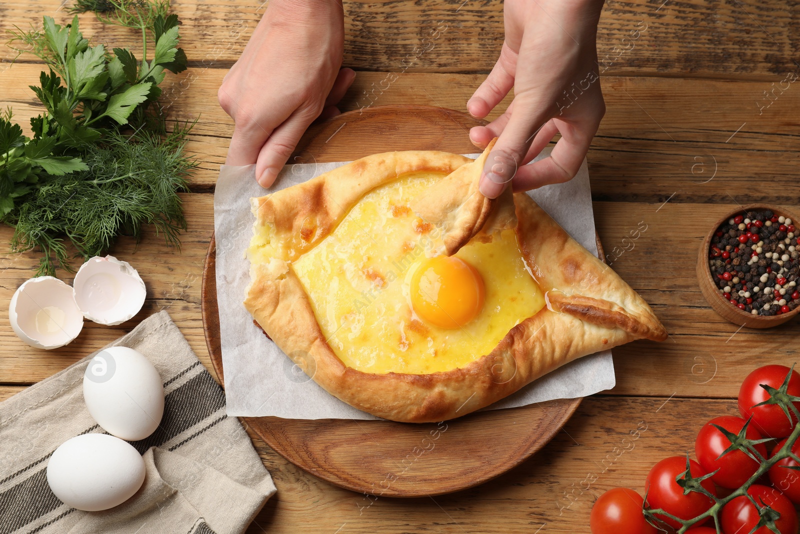 Woman eating delicious khachapuri at wooden table, top view Photo of Woman eating delicious khachapuri at wooden table, top view