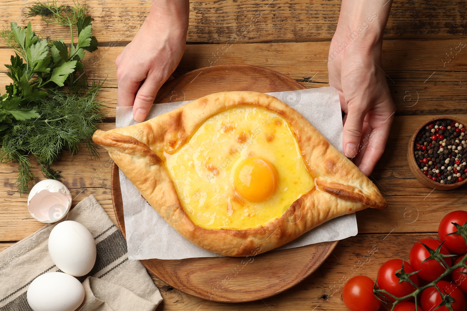 Woman with delicious khachapuri at wooden table, top view Photo of Woman with delicious khachapuri at wooden table, top view
