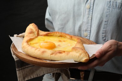 Photo of Woman with delicious khachapuri on black background, closeup