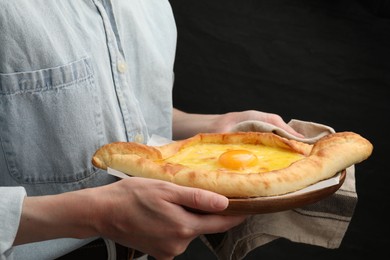 Photo of Woman with delicious khachapuri on black background, closeup