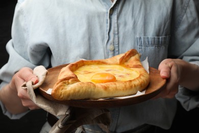Photo of Woman with delicious khachapuri on black background, closeup
