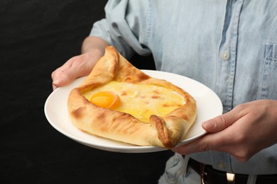 Photo of Woman with delicious khachapuri on black background, closeup
