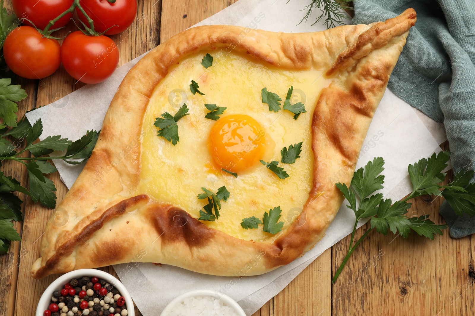 Tasty khachapuri with cheese, egg, tomatoes, parsley and spices on wooden table, flat lay Photo of Tasty khachapuri with cheese, egg, tomatoes, parsley and spices on wooden table, flat lay