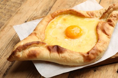 Photo of Tasty khachapuri with cheese and egg on wooden table, closeup