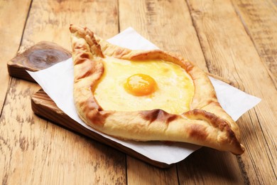 Photo of Tasty khachapuri with cheese and egg on wooden table, closeup