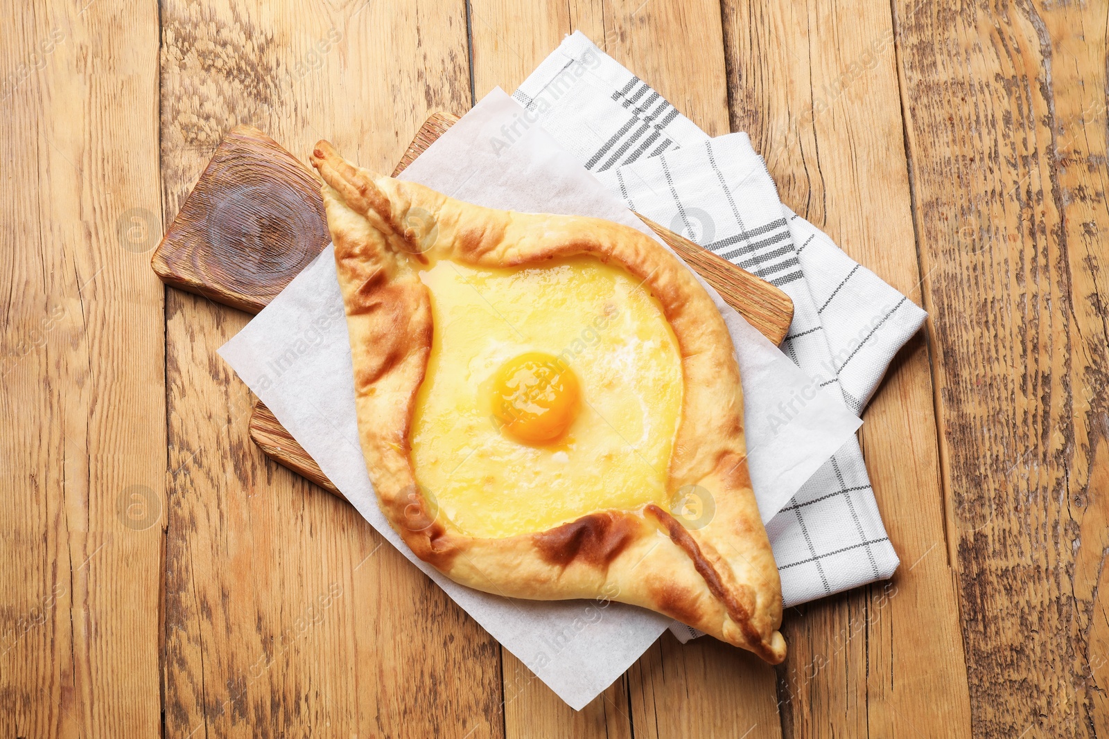Photo of Tasty khachapuri with cheese and egg on wooden table, top view