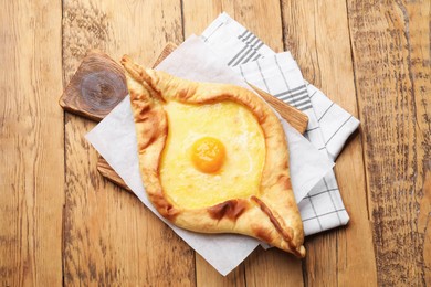 Photo of Tasty khachapuri with cheese and egg on wooden table, top view