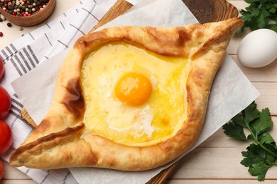 Photo of Tasty khachapuri with cheese and egg served on wooden table, flat lay