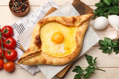 Photo of Tasty khachapuri with cheese and egg served on wooden table, flat lay