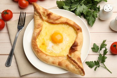 Photo of Tasty khachapuri with cheese and egg served on wooden table, flat lay