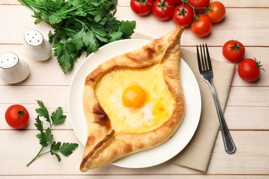 Photo of Tasty khachapuri with cheese and egg served on wooden table, flat lay