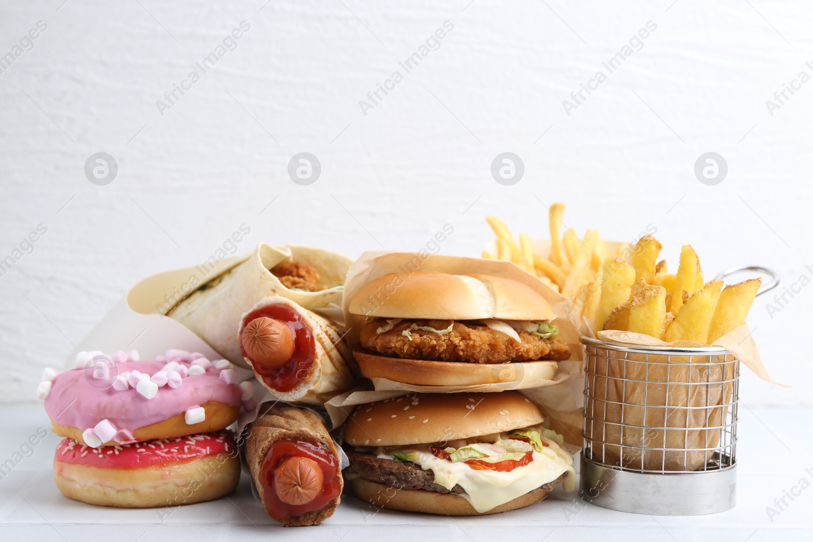 Different delicious fast food on white table, closeup Photo of Different delicious fast food on white table, closeup