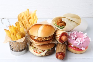 Photo of Different delicious fast food on white table, closeup