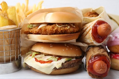 Photo of Different delicious fast food on white table, closeup