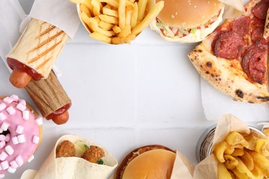 Photo of Different delicious fast food on white tiled table, flat lay. Space for text