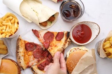 Photo of Woman taking piece of pizza at white marble table, top view