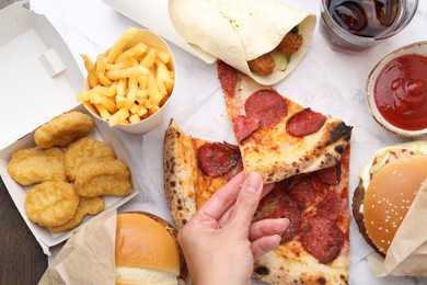 Photo of Woman taking piece of pizza at table, top view