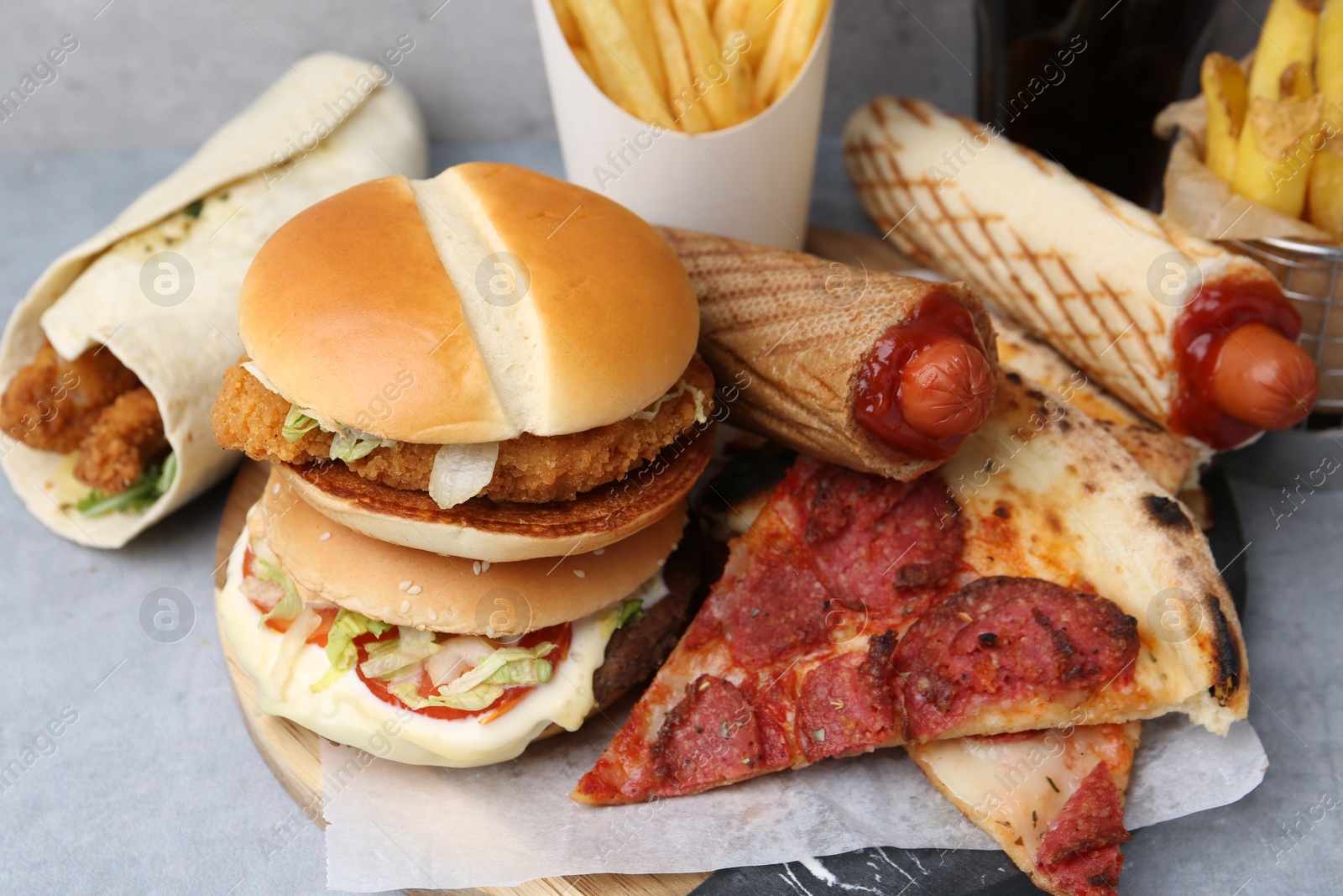 Different delicious fast food on grey table, closeup Photo of Different delicious fast food on grey table, closeup