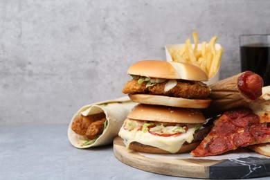 Photo of Different delicious fast food and soda drink on grey table, closeup. Space for text