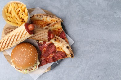 Photo of Different delicious fast food on grey table, top view. Space for text