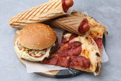 Photo of Different delicious fast food on grey table, closeup