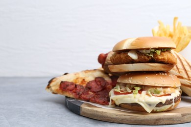 Photo of Different delicious fast food on grey table, closeup. Space for text