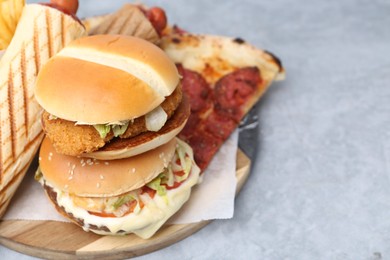 Photo of Different delicious fast food on grey table, closeup. Space for text