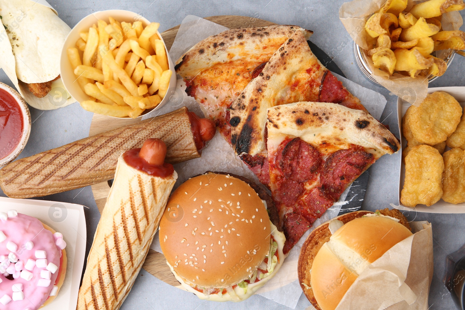 Different delicious fast food on grey table, flat lay Photo of Different delicious fast food on grey table, flat lay
