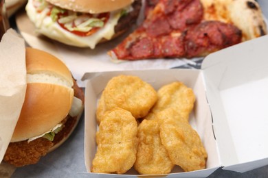 Photo of Different delicious fast food on grey table, closeup