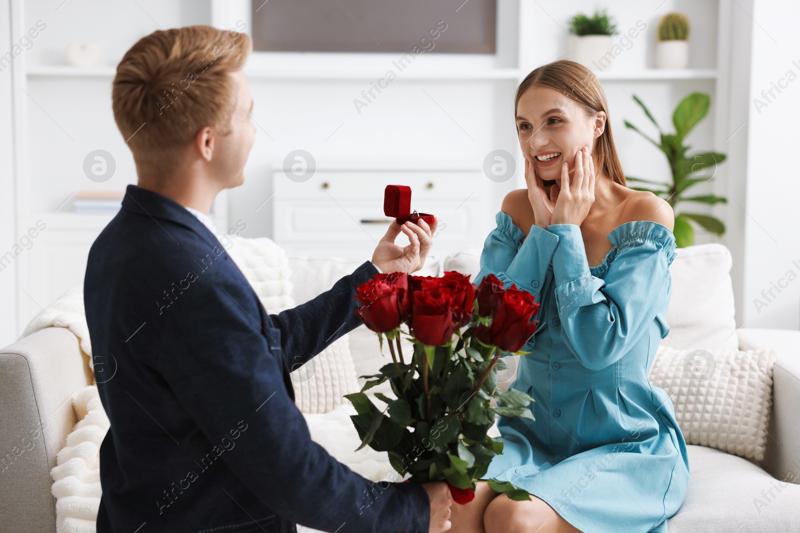 Man with engagement ring and bouquet of roses making marriage proposal to his happy girlfriend at home Photo of Man with engagement ring and bouquet of roses making marriage proposal to his happy girlfriend at home