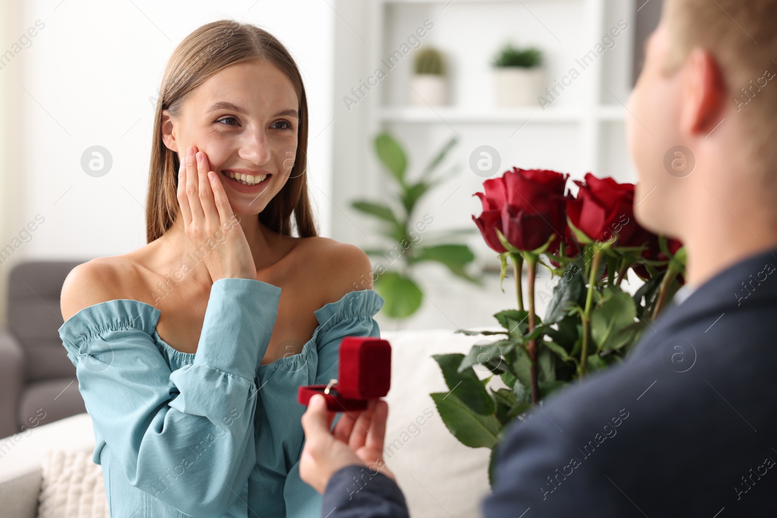 Man with engagement ring and bouquet of roses making marriage proposal to his happy girlfriend at home, closeup Photo of Man with engagement ring and bouquet of roses making marriage proposal to his happy girlfriend at home, closeup