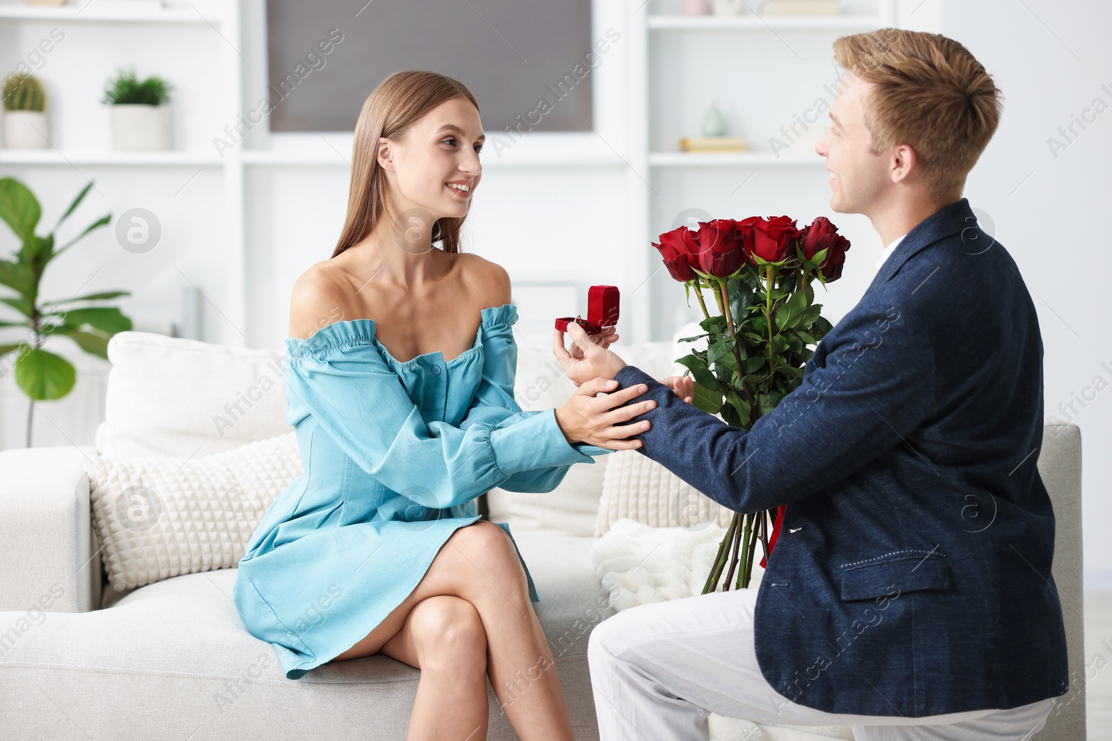 Man with engagement ring and bouquet of roses making marriage proposal to his happy girlfriend at home Photo of Man with engagement ring and bouquet of roses making marriage proposal to his happy girlfriend at home