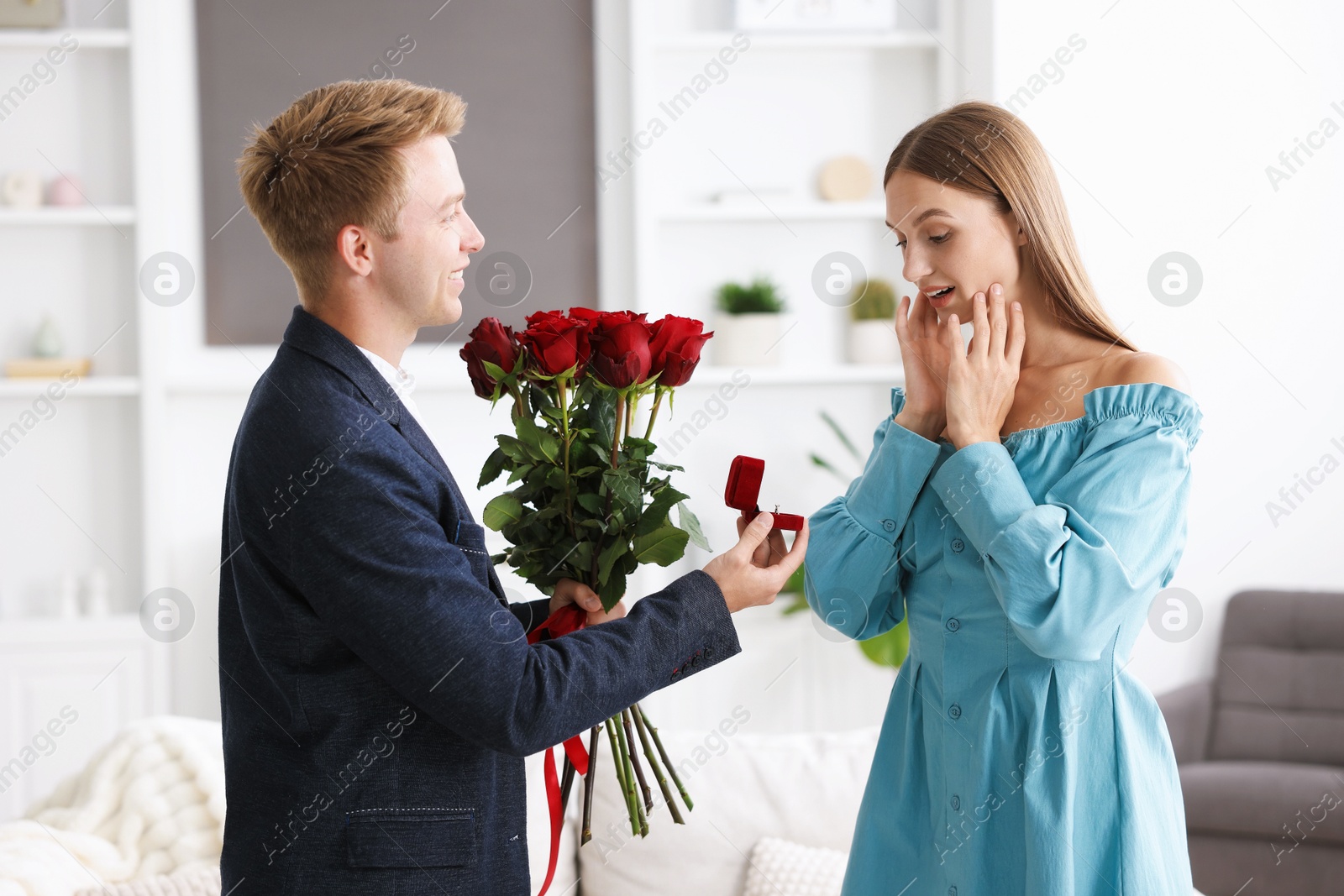 Man with engagement ring and bouquet of roses making marriage proposal to his happy girlfriend at home Photo of Man with engagement ring and bouquet of roses making marriage proposal to his happy girlfriend at home