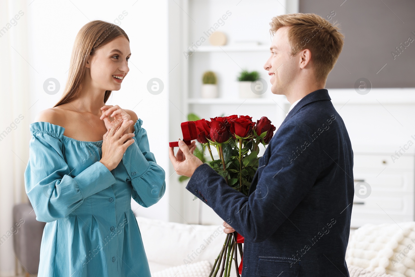 Man with engagement ring and bouquet of roses making marriage proposal to his happy girlfriend at home Photo of Man with engagement ring and bouquet of roses making marriage proposal to his happy girlfriend at home