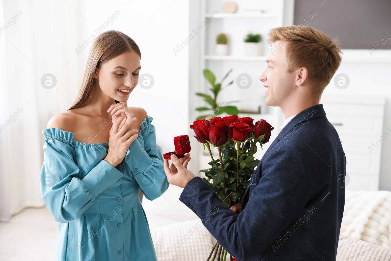 Man with engagement ring and bouquet of roses making marriage proposal to his happy girlfriend at home Photo of Man with engagement ring and bouquet of roses making marriage proposal to his happy girlfriend at home