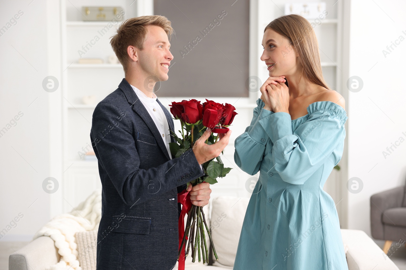 Man with engagement ring and bouquet of roses making marriage proposal to his happy girlfriend at home Photo of Man with engagement ring and bouquet of roses making marriage proposal to his happy girlfriend at home