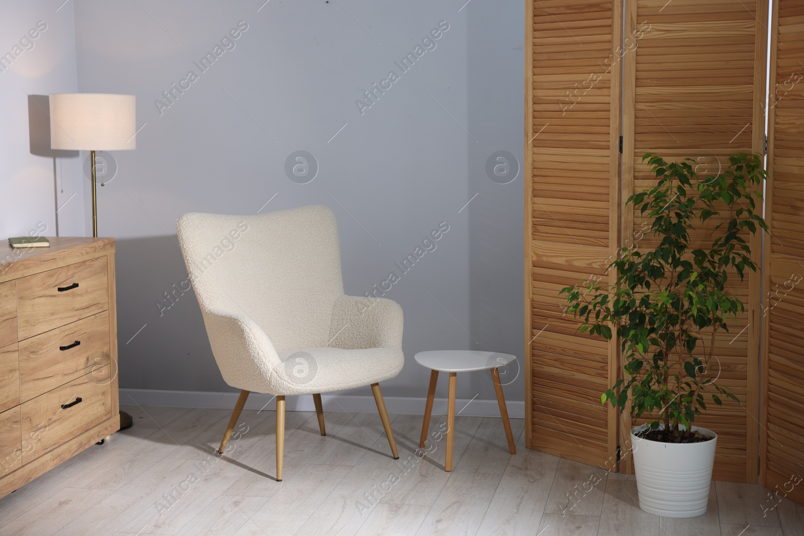Soft armchair and coffee table near grey wall indoors. Interior design Photo of Soft armchair and coffee table near grey wall indoors. Interior design