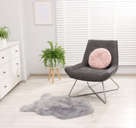 Photo of Soft armchair, cushion, rug and houseplant in light room. Interior design