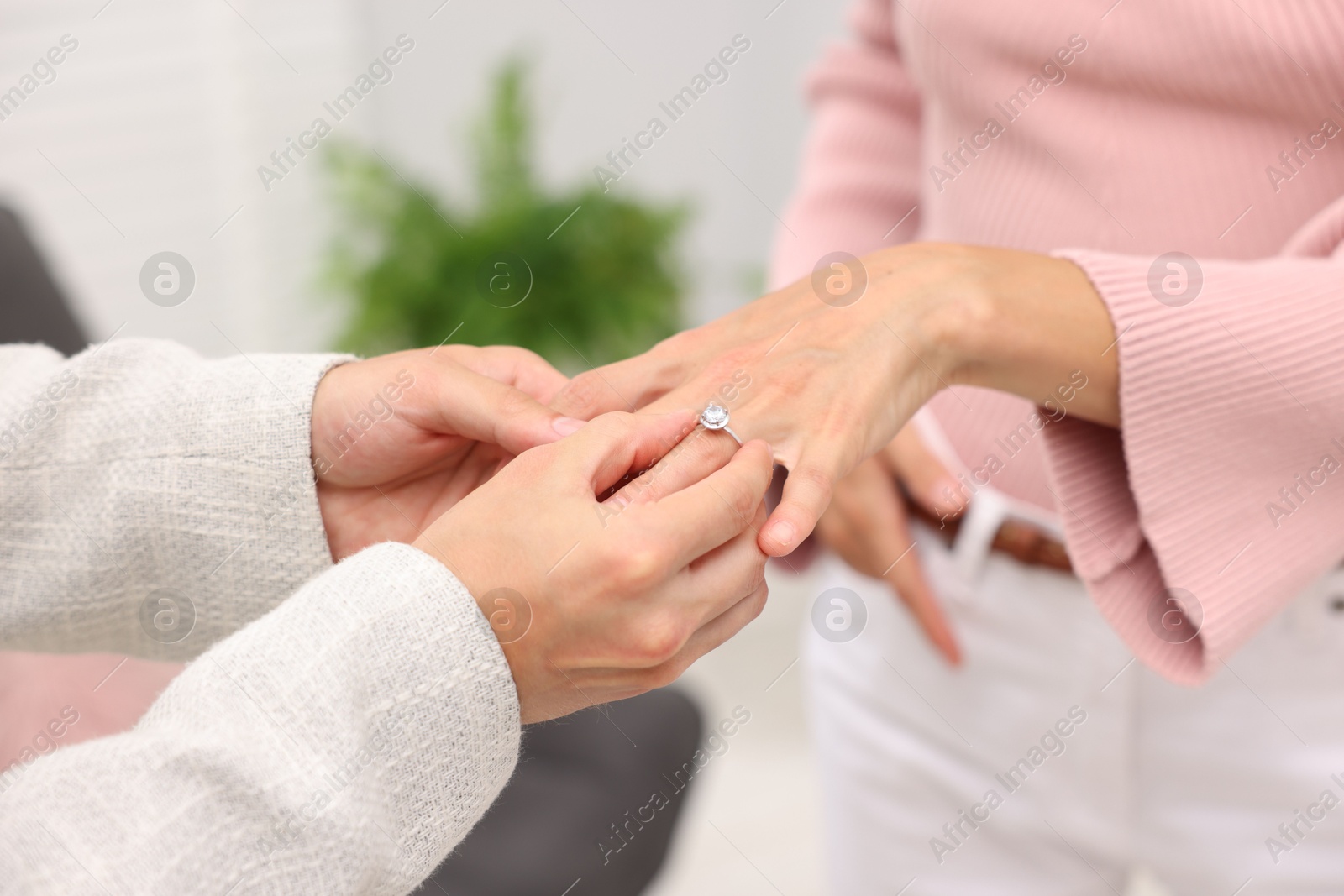 Making marriage proposal. Man putting engagement ring onto his girlfriend's finger at home, closeup Photo of Making marriage proposal. Man putting engagement ring onto his girlfriend's finger at home, closeup
