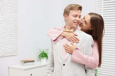 Photo of Making marriage proposal. Woman with engagement ring and her smiling fiance hugging in light room. Space for text