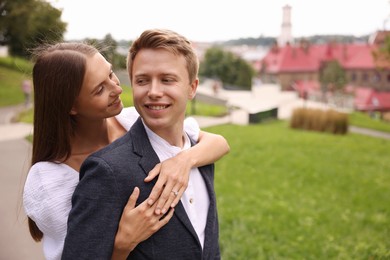 Photo of Marriage proposal. Woman with engagement ring hugging her smiling fiance outdoors, space for text