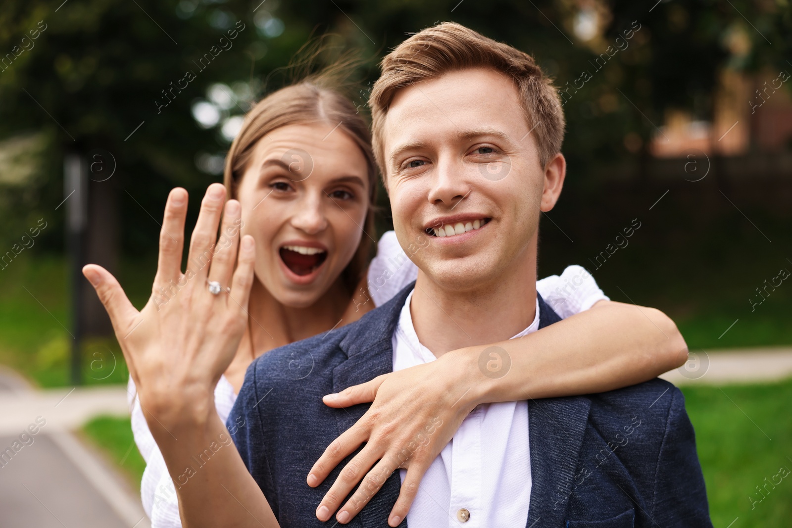 Marriage proposal. Excited woman showing engagement ring and hugging her fiance outdoors Photo of Marriage proposal. Excited woman showing engagement ring and hugging her fiance outdoors